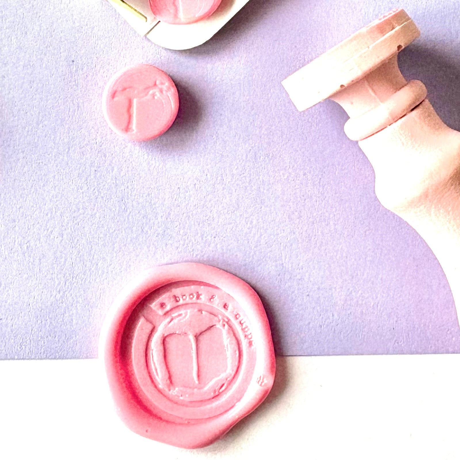 Pink hand crafted wax seal stamp featuring a pink wax seal stamped with a logo. hand made by British stamp maker.