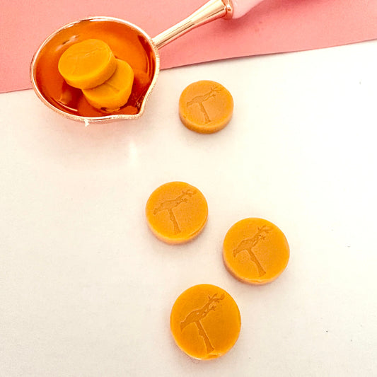 Apricot sealing wax beads in melting spoon, for vintage-style crafting.