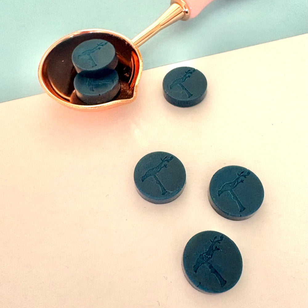 Deep blue sealing wax beads with pink spoon, ready for sealing invitations.
