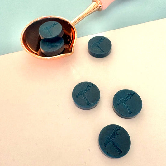 Deep blue sealing wax beads with pink spoon, ready for sealing invitations.