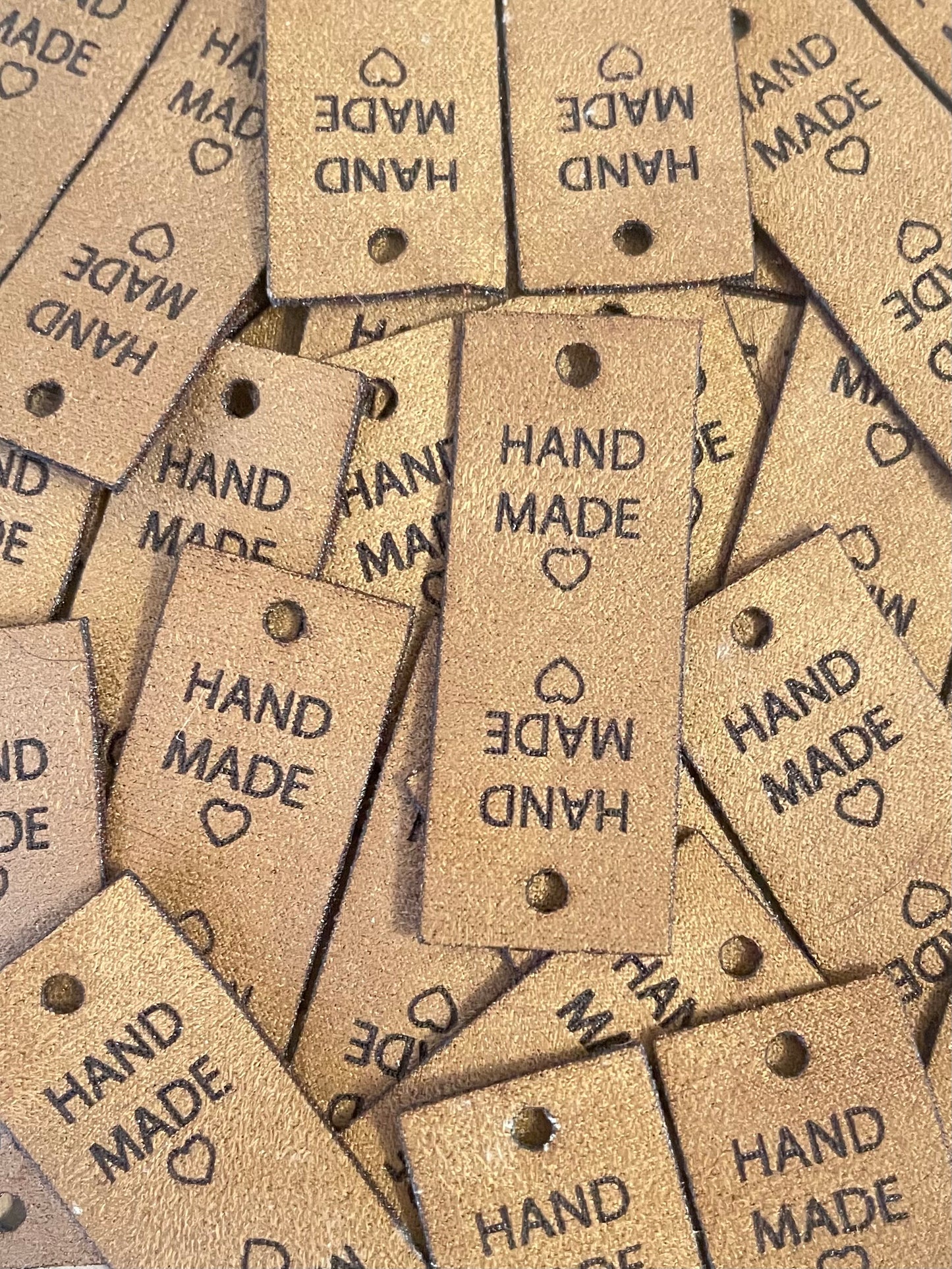 Brown faux suede tags with square edges and one hole for a rivet fastener. Featuring hand made text and a heart. The tag is foldable for use on crochet hats, scarfs, gloves, booties and knitted socks, beanies and more.
