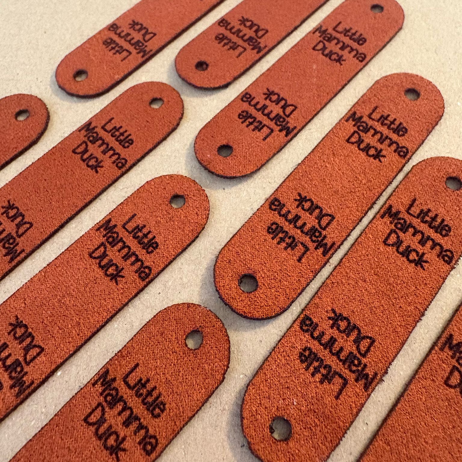 Burnt orange faux suede labels with a rivet hold on either end.