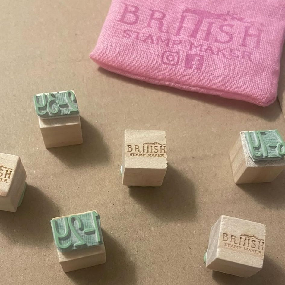 Collection of wooden stamps with 'British Stamp Maker' branding on a brown surface.