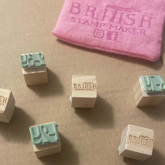 Collection of wooden stamps with 'British Stamp Maker' branding on a brown surface.