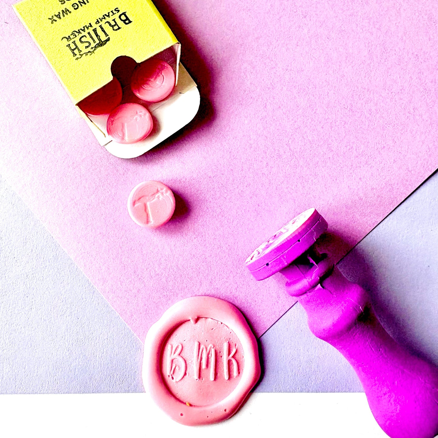 Custom wax sealing stamp handcrafted in bold purple, featuring a pink wax seal and had poured sealing wax beads made by British stamp maker.