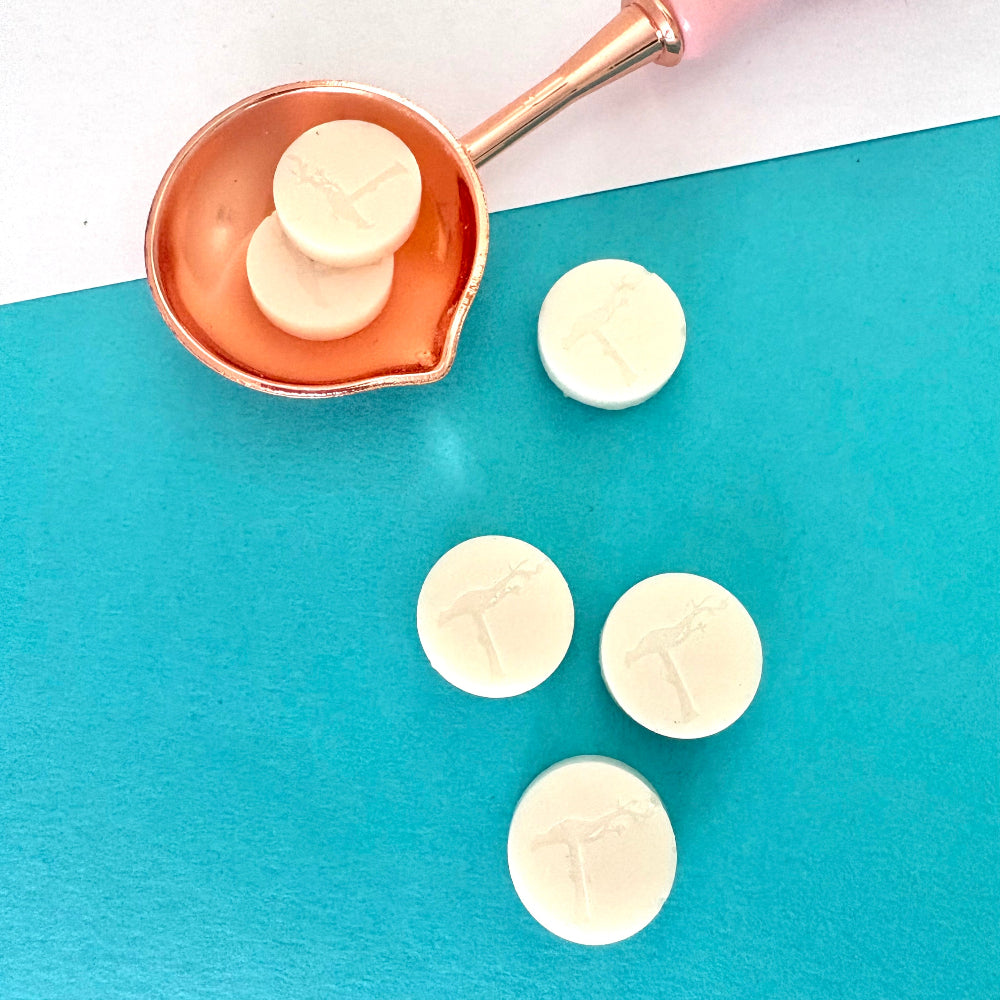 Pure white sealing wax beads in a pink melting spoon, ready for crafting.
